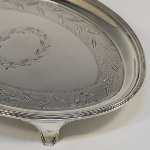 A very handsome Antique Georgian Sterling Silver teapot stand, having an oval body with a band of hand-engraved floral decoration, a central vacant laurel-leaf cartouche, a raised border with an applied reeded edge, and sitting on four flange feet. This elegant antique silver teapot stand
was made in London in 1796. The dimensions of this fine hand-made antique silver teapot stand are length 17 cms (6.75 inches), width 12 cms (4.75 inches), and it weighs approx. 127g (4 troy ounces).