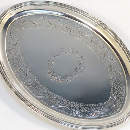 A very handsome Antique Georgian Sterling Silver teapot stand, having an oval body with a band of hand-engraved floral decoration, a central vacant laurel-leaf cartouche, a raised border with an applied reeded edge, and sitting on four flange feet. This elegant antique silver teapot stand
was made in London in 1796. The dimensions of this fine hand-made antique silver teapot stand are length 17 cms (6.75 inches), width 12 cms (4.75 inches), and it weighs approx. 127g (4 troy ounces).