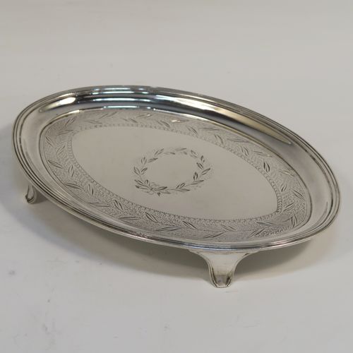 A very handsome Antique Georgian Sterling Silver teapot stand, having an oval body with a band of hand-engraved floral decoration, a central vacant laurel-leaf cartouche, a raised border with an applied reeded edge, and sitting on four flange feet. This elegant antique silver teapot stand
was made in London in 1796. The dimensions of this fine hand-made antique silver teapot stand are length 17 cms (6.75 inches), width 12 cms (4.75 inches), and it weighs approx. 127g (4 troy ounces).