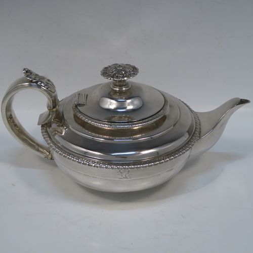 A very handsome Antique Georgian Sterling Silver teapot, having a round bellied bellied body with t applied gadroon borders, an insulated scroll handle with Anthemion leaf thumb-piece, a hinged domed lid with cast floral finial, a plain scoll spout, and all sitting on a round collet foot. This elegant silver teapot eas made by George Fox  of London in 1826. The dimensions of this fine hand-made antique silver teapot are length 27.5 cms (10.75 inches), diameter of main body 18 cms (7 inches), height 12.5 cms (5 inches), and it weighs approx. 800g (25.8 troy ounces).   
