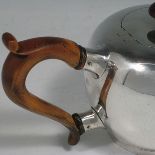 Antique Georgian sterling silver teapot in an early George II Bullet style, having a plain round baluster body, straight tapering spout, wooden scroll handle and finial, an invisibly hinged flat lid, and sitting on a collet foot. Made by George Greenhill Jones of London in 1730. The dimensions of this fine hand-made silver teapot are length 21 cms (8.25 inches), height 11 cms (4.3 inches), and it weighs approx. 445g (14.4 troy ounces). Please note that this teapot is crested on one side with a full armorial crest.