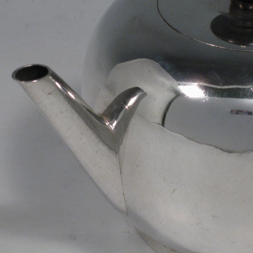 Antique Georgian sterling silver teapot in an early George II Bullet style, having a plain round baluster body, straight tapering spout, wooden scroll handle and finial, an invisibly hinged flat lid, and sitting on a collet foot. Made by George Greenhill Jones of London in 1730. The dimensions of this fine hand-made silver teapot are length 21 cms (8.25 inches), height 11 cms (4.3 inches), and it weighs approx. 445g (14.4 troy ounces). Please note that this teapot is crested on one side with a full armorial crest.