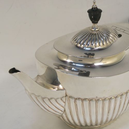 A very handsome Antique Victorian Sterling Silver teapot, having an oval body with hand-chased straight half fluting, a wooden insulated handle, a hinged domed lid with fluting, a wooden finial, and all sitting on a collet foot. This elegant antique silver teapot was made by Edward Hutton of London in 1891. The dimensions of this fine hand-made antique silver teapot are height 15 cms (6 inches), length 27.5 cms (10.75 inches), and it weighs approx. 550g (17.7 troy ounces).