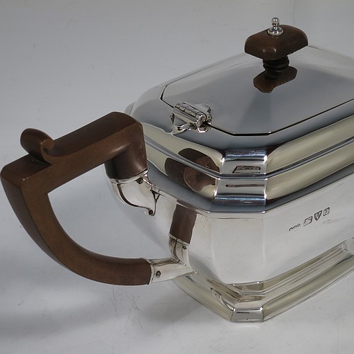 A very handsome Sterling Silver Art Deco teapot, in a plain elongated octagonal panelled style, having a hinged lid with a wooden finial, a wooden insulated handle, a plain curved spout, and all sitting on a matching pedestal foot. Made by Henry Clifford Davis of Chester in 1934. The dimensions of this fine hand-made Art Deco silver teapot are height 14 cms (5.5 inches), length 30.5 cms (12 inches), and it weighs approx. 650g (21 troy ounces).