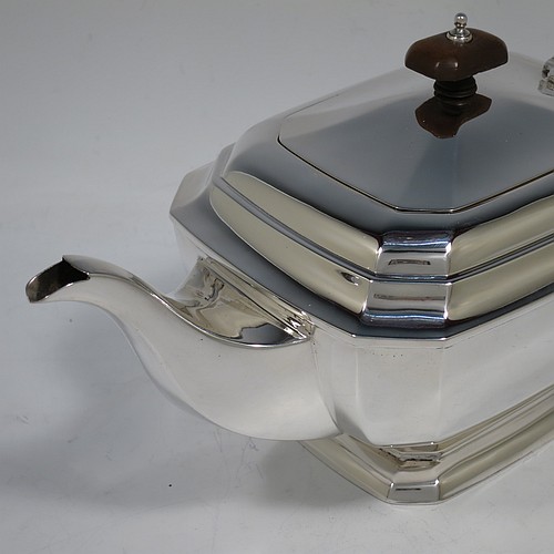 A very handsome Sterling Silver Art Deco teapot, in a plain elongated octagonal panelled style, having a hinged lid with a wooden finial, a wooden insulated handle, a plain curved spout, and all sitting on a matching pedestal foot. Made by Henry Clifford Davis of Chester in 1934. The dimensions of this fine hand-made Art Deco silver teapot are height 14 cms (5.5 inches), length 30.5 cms (12 inches), and it weighs approx. 650g (21 troy ounces).