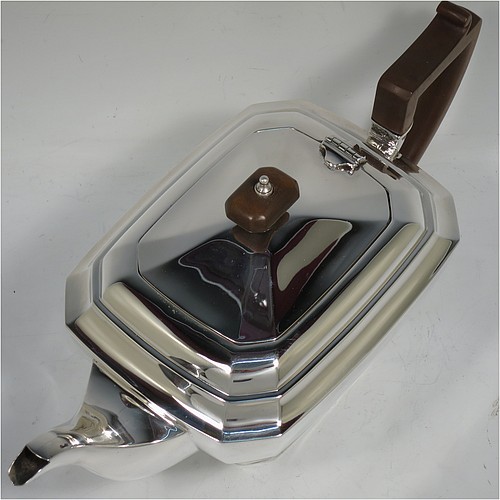A very handsome Sterling Silver Art Deco teapot, in a plain elongated octagonal panelled style, having a hinged lid with a wooden finial, a wooden insulated handle, a plain curved spout, and all sitting on a matching pedestal foot. Made by Henry Clifford Davis of Chester in 1934. The dimensions of this fine hand-made Art Deco silver teapot are height 14 cms (5.5 inches), length 30.5 cms (12 inches), and it weighs approx. 650g (21 troy ounces).