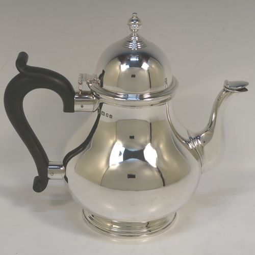 A heavy and very handsome Sterling Silver teapot, in a George I style with a plain round bellied body, having a hinged domed lid with cast finial, a wooden insulated handle, a curved and panelled spout, and all sitting on a round collet foot. This elegant silver teapot was made by Ellis Jacob Greenberg of London in 1928. The dimensions of this fine hand-made heavy silver teapot are height 19 cms (7.5 inches), length 21 cms (8.25 inches), and it weighs approx. 613g (19.8 troy ounces).  