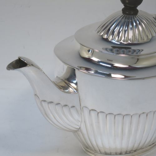 A very handsome Antique Edwardian Sterling Silver teapot, having an oval body with hand-chased straight half fluting, a wooden insulated handle, a hinged domed lid with fluting, a wooden finial, and all sitting on a collet foot. Made by Elkington and Co. Ltd., of Birmingham in 1902. The dimensions of this fine hand-made antique silver teapot are height 14.5 cms (5.75 inches), length 24 cms (9.5 inches), and it weighs is approx. 450g (14.5 troy ounces).