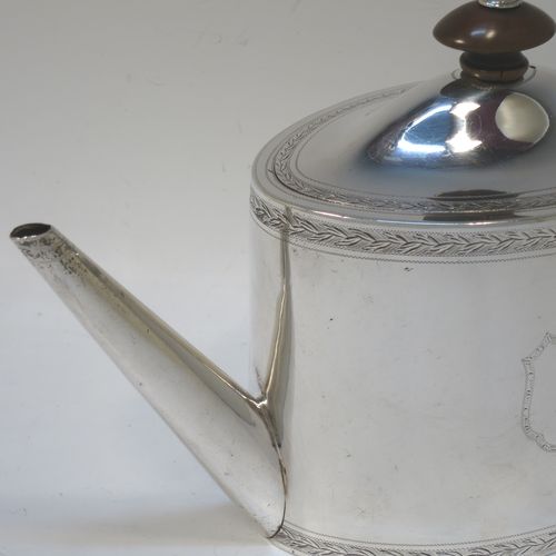 A very handsome Neoclassical style Antique Georgian Sterling Silver teapot, having an oval straight-sided body with hand-engraved upper and lower bands of floral work, with engraved cartouches on both sides, a straight tapering spout, a wooden scroll handle and oval finial, an invisibly hinged domed lid with matching engraving, and all sitting on a flat base. Made by Henry Chawner of London in 1794. The dimensions of this fine hand-made antique silver teapot are length 26 cms (10 inches), height 15 cms (6 inches), and it weighs approx. 350g (11.3 troy ounces). Please note that this item is crested.