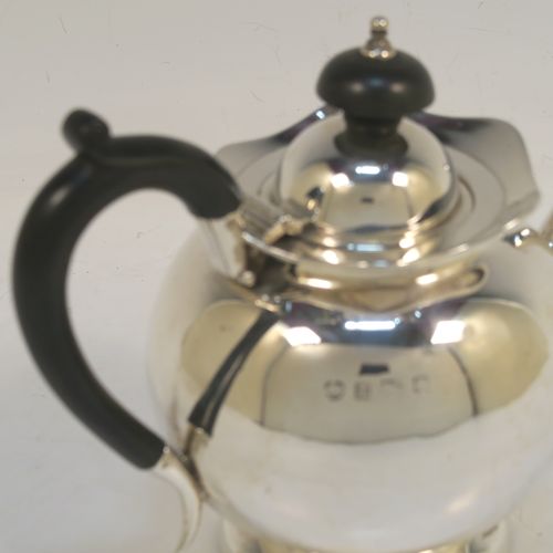 A small and pretty Antique Edwardian Sterling Silver bachelor size teapot, having a plain round bellied body, a wooden insulated handle, a hinged domed lid and wooden finial, and all sitting on a pedestal foot. This elegant antique silver teapot was made by Williams Ltd., of Birmingham in 1907. The dimensions of this fine hand-made silver bachelor teapot are height 12.5 cms (5 inches), length 17.5 cms (7 inches), and it weighs is approx. 250g (8 troy ounces).