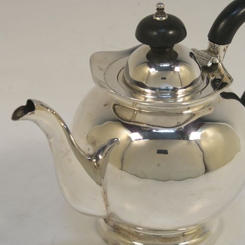 A small and pretty Antique Edwardian Sterling Silver bachelor size teapot, having a plain round bellied body, a wooden insulated handle, a hinged domed lid and wooden finial, and all sitting on a pedestal foot. This elegant antique silver teapot was made by Williams Ltd., of Birmingham in 1907. The dimensions of this fine hand-made silver bachelor teapot are height 12.5 cms (5 inches), length 17.5 cms (7 inches), and it weighs is approx. 250g (8 troy ounces).