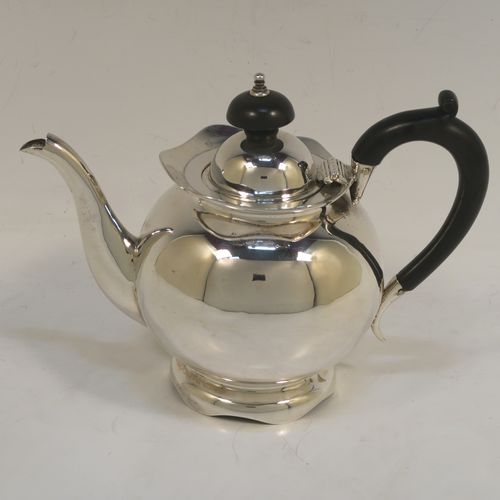A small and pretty Antique Edwardian Sterling Silver bachelor size teapot, having a plain round bellied body, a wooden insulated handle, a hinged domed lid and wooden finial, and all sitting on a pedestal foot. This elegant antique silver teapot was made by Williams Ltd., of Birmingham in 1907. The dimensions of this fine hand-made silver bachelor teapot are height 12.5 cms (5 inches), length 17.5 cms (7 inches), and it weighs is approx. 250g (8 troy ounces).
