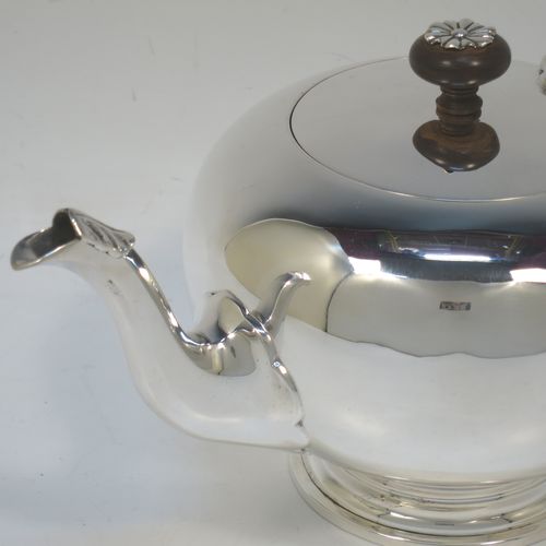 A very handsome Sterling Silver bachelor size teapot in an early George II Bullet or Skittle Ball style, having a plain round bellied body, a curved spout, a wooden scroll handle and finial with silver mount, a hinged lid, and sitting on a pedestal foot. Made by Mappin and Webb of London in 1926. The dimensions of this fine hand-made silver bachelor teapot are length 23 cms (9 inches), height 12 cms (4.75 inches), and it weighs approx. 350g (11.3 troy ounces).
