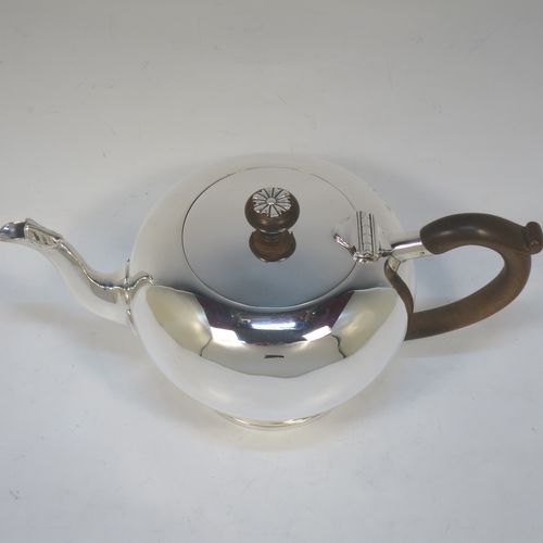 A very handsome Sterling Silver bachelor size teapot in an early George II Bullet or Skittle Ball style, having a plain round bellied body, a curved spout, a wooden scroll handle and finial with silver mount, a hinged lid, and sitting on a pedestal foot. Made by Mappin and Webb of London in 1926. The dimensions of this fine hand-made silver bachelor teapot are length 23 cms (9 inches), height 12 cms (4.75 inches), and it weighs approx. 350g (11.3 troy ounces).