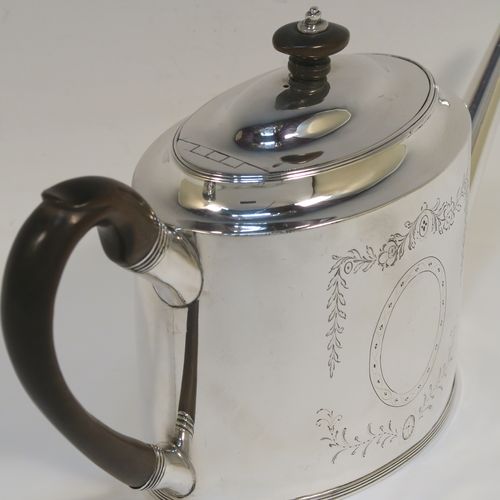 A very handsome Neoclassical style Antique Georgian Sterling Silver teapot, having an oval straight-sided body, with hand-engraved floral swags surrounding vacant cartouches on both sides, a straight tapering spout, a wooden scroll handle and oval finial, an invisibly hinged domed lid, and all sitting on a flat base with a reeded border. This very elegant antique silver teapot was made by Peter and Anne Bateman of London in 1792. The dimensions of this fine hand-made antique silver teapot are length 25.5 cms (10 inches), height 14 cms (5.5 inches), and it weighs approx. 350g (11.3 troy ounces).