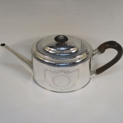 A very handsome Neoclassical style Antique Georgian Sterling Silver teapot, having an oval straight-sided body, with hand-engraved floral swags surrounding vacant cartouches on both sides, a straight tapering spout, a wooden scroll handle and oval finial, an invisibly hinged domed lid, and all sitting on a flat base with a reeded border. This very elegant antique silver teapot was made by Peter and Anne Bateman of London in 1792. The dimensions of this fine hand-made antique silver teapot are length 25.5 cms (10 inches), height 14 cms (5.5 inches), and it weighs approx. 350g (11.3 troy ounces).