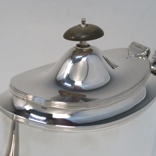 A very handsome Neoclassical style Antique Sterling Silver teapot, having a very plain oval straight-sided body with applied reeded borders, a straight tapering spout, a wooden scroll handle, a hinged domed lid with an oval wooden finial, and all sitting on a flat base. This very elegant antique silver teapot was made by Robert Stewart of Birmingham in 1922. The dimensions of this fine hand-made antique silver teapot are length 27 cms (10.5 inches), height 14 cms (5.5 inches), and it weighs approx. 450g (14.5 troy ounces).