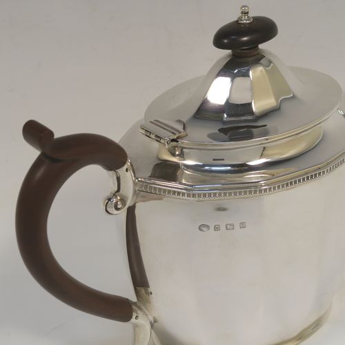 A very handsome Sterling Silver teapot, having a plain oval body with paneled curved sides and an applied gadroon border, a straight tapering spout, a wooden scroll handle and finial, and all sitting on a flat base. This elegant silver teapot was made by Alexander Clarke of Birmingham in 1932. The dimensions of this fine hand-made silver teapot are length 28 cms (11 inches), height 16.5 cms (6.5 inches), and it weighs approx. 530g (17 troy ounces).