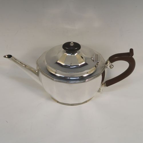 A very handsome Sterling Silver teapot, having a plain oval body with paneled curved sides and an applied gadroon border, a straight tapering spout, a wooden scroll handle and finial, and all sitting on a flat base. This elegant silver teapot was made by Alexander Clarke of Birmingham in 1932. The dimensions of this fine hand-made silver teapot are length 28 cms (11 inches), height 16.5 cms (6.5 inches), and it weighs approx. 530g (17 troy ounces).