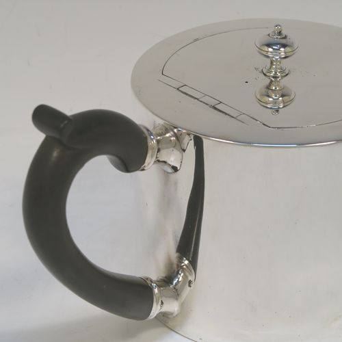 A very stylish and handsome Antique Victorian Sterling Silver teapot, having a very plain round straight-sided body, a straight tapering spout, a wooden scroll handle, an invisibly hinged flat lid with a cast round finial, and all sitting on a flat base. This beautiful antique silver teapot was made by Charles Stuart Harris of London in 1870. The dimensions of this fine hand-made antique silver teapot are length 23 cms (9 inches), height 11.5 cms (4.5 inches), diameter of main body 11 cms (4.3 inches), and it weighs approx. 450g (14.5 troy ounces).