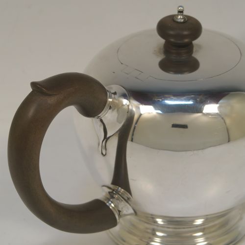 A very handsome Sterling Silver teapot in an early George II Bullet or Skittle Ball style, having a very plain round bellied body, a straight tapering spout, a wooden scroll handle and finial, an invisibly hinged flat lid, and sitting on a pedestal foot. This elegant silver teapot was made by D. and J. Welby of London in 1927. The dimensions of this fine hand-made silver skittle ball style teapot are length 22.5 cms (8.75 inches), height 13 cms (5 inches), and it weighs approx. 500g (16 troy ounces). Please note that this item is crested on one side.