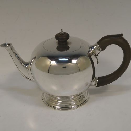 A very handsome Sterling Silver teapot in an early George II Bullet or Skittle Ball style, having a very plain round bellied body, a straight tapering spout, a wooden scroll handle and finial, an invisibly hinged flat lid, and sitting on a pedestal foot. This elegant silver teapot was made by D. and J. Welby of London in 1927. The dimensions of this fine hand-made silver skittle ball style teapot are length 22.5 cms (8.75 inches), height 13 cms (5 inches), and it weighs approx. 500g (16 troy ounces). Please note that this item is crested on one side.