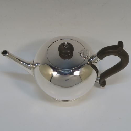 A very handsome Sterling Silver teapot in an early George II Bullet or Skittle Ball style, having a very plain round bellied body, a straight tapering spout, a wooden scroll handle and finial, a hinged flat lid, and sitting on a pedestal foot. This elegant silver teapot was made by Wakely and Wheeler of London in 1936. The dimensions of this fine hand-made silver skittle ball style teapot are length 20 cms (8 inches), height 12 cms (4.75 inches), and it weighs approx. 280g (9 troy ounces).