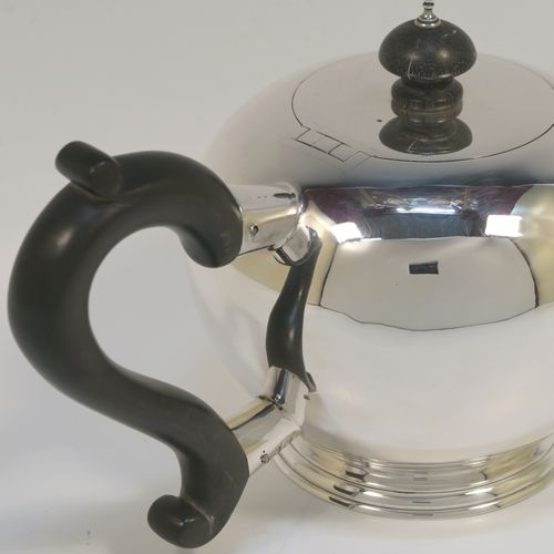 A very handsome Antique Sterling Silver teapot in an early George II Bullet or Skittle Ball style, having a very plain round bellied body, a straight tapering spout, a wooden scroll handle and finial, an invisibly hinged flat lid, and sitting on a pedestal foot. This elegant antique silver teapot was made by Charles Stuart Harris of London in 1919. The dimensions of this fine hand-made silver skittle ball style teapot are length 25.5 cms (10 inches), height 13 cms (5 inches), and it weighs approx. 500g (16 troy ounces).