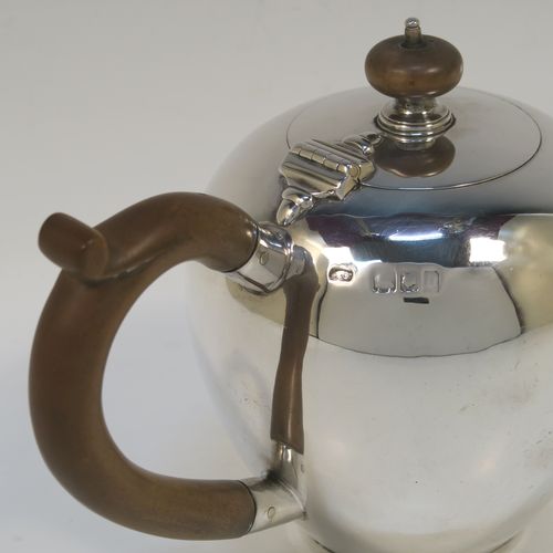 A very handsome Antique Sterling Silver teapot in an early George II Bullet or Skittle Ball style, having a very plain round bellied body, a straight tapering spout, a wooden scroll handle and finial, a hinged flat lid, and sitting on a collet foot. This elegant silver teapot was made by Alexander Osborne London in 1917. The dimensions of this fine hand-made silver skittle ball style teapot are length 23 cms (9 inches), height 12.5 cms 5 inches), and it weighs approx. 340g 11 troy ounces).