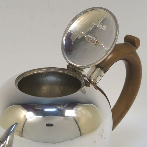 A very handsome Antique Sterling Silver teapot in an early George II Bullet or Skittle Ball style, having a very plain round bellied body, a straight tapering spout, a wooden scroll handle and finial, a hinged flat lid, and sitting on a collet foot. This elegant silver teapot was made by Alexander Osborne London in 1917. The dimensions of this fine hand-made silver skittle ball style teapot are length 23 cms (9 inches), height 12.5 cms 5 inches), and it weighs approx. 340g 11 troy ounces).