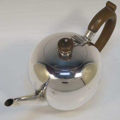 A very handsome Antique Sterling Silver teapot in an early George II Bullet or Skittle Ball style, having a very plain round bellied body, a straight tapering spout, a wooden scroll handle and finial, a hinged flat lid, and sitting on a collet foot. This elegant silver teapot was made by Alexander Osborne London in 1917. The dimensions of this fine hand-made silver skittle ball style teapot are length 23 cms (9 inches), height 12.5 cms 5 inches), and it weighs approx. 340g 11 troy ounces).