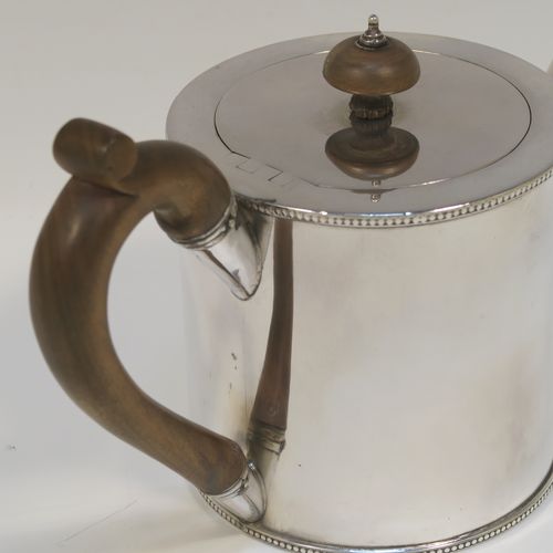 A very handsome Neoclassical style Antique Georgian Sterling Silver Saffron teapot in a very plain round straight-sided body, with applied bead-edged borders, a straight tapering spout, a wooden scroll handle and round finial, an invisibly hinged flat lid, and all sitting on a flat base. This beautiful antique silver saffron teapot was made by Walter Brind of London in 1774. The dimensions of this fine hand-made antique silver teapot are length 22 cms (8.75 inches), height 13.5 cms (5.3 inches), and it weighs approx. 450g (14.5 troy ounces).