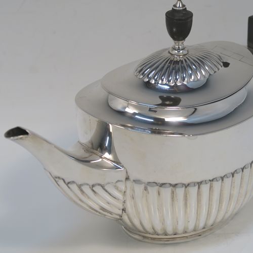 A very handsome Antique Sterling Silver teapot, having an oval body with hand-chased straight half fluting, a wooden insulated handle, a hinged domed lid with fluting, a wooden finial, and all sitting on a collet foot. This elegant silver teapot was made by William Hutton and Sons of Sheffield in 1926. The dimensions of this fine hand-made antique silver teapot are height 14.5 cms (5.75 inches), length 26 cms (10.25 inches), and it weighs is approx. 450g (14.5 troy ounces).