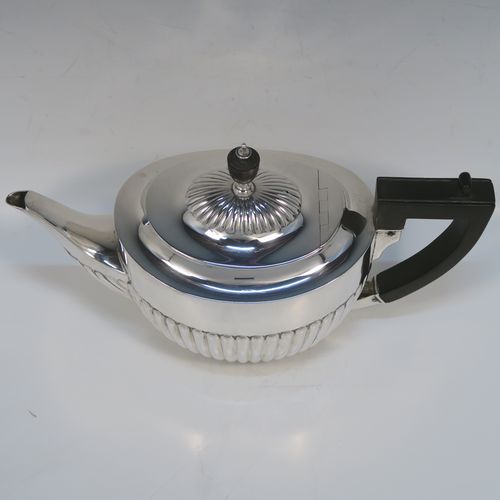 A very handsome Antique Sterling Silver teapot, having an oval body with hand-chased straight half fluting, a wooden insulated handle, a hinged domed lid with fluting, a wooden finial, and all sitting on a collet foot. This elegant silver teapot was made by William Hutton and Sons of Sheffield in 1926. The dimensions of this fine hand-made antique silver teapot are height 14.5 cms (5.75 inches), length 26 cms (10.25 inches), and it weighs is approx. 450g (14.5 troy ounces).