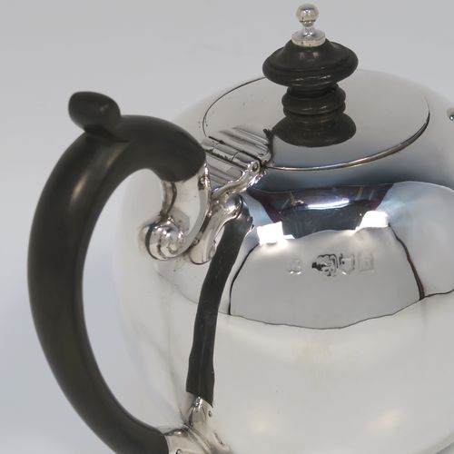 A small but beautifully made Antique Victorian Sterling Silver teapot in an early George II Bullet or Skittle Ball style, having a very plain round bellied body, a curved spout, a wooden scroll handle and finial, a hinged flat lid, and sitting flat base. This elegant silver bachelor sized teapot was made by Wakely and Wheeler of London in 1897. The dimensions of this fine hand-made silver skittle ball style teapot are length 17 cms (6.75 inches), height 11.5 cms (4.5 inches), and it weighs approx. 200g (6.5 troy ounces).