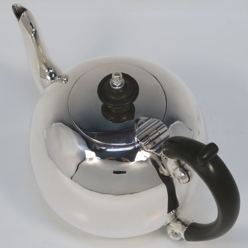 A small but beautifully made Antique Victorian Sterling Silver teapot in an early George II Bullet or Skittle Ball style, having a very plain round bellied body, a curved spout, a wooden scroll handle and finial, a hinged flat lid, and sitting flat base. This elegant silver bachelor sized teapot was made by Wakely and Wheeler of London in 1897. The dimensions of this fine hand-made silver skittle ball style teapot are length 17 cms (6.75 inches), height 11.5 cms (4.5 inches), and it weighs approx. 200g (6.5 troy ounces).