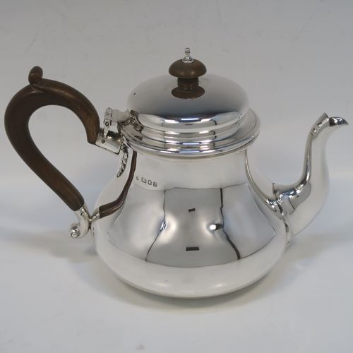 A very handsome Sterling Silver Bachelor size teapot, in a George I style with a plain round bellied body, having a hinged domed lid with wooden finial, a wooden insulated handle, a curved spout, and all sitting on a flat base. This elegant silver teapot was made by Charles Stuart Harris of London in 1923. The dimensions of this fine hand-made  silver Bachelor teapot are height 14 cms (5.5 inches), length 21 cms (8.25 inches), and it weighs approx. 445g (14 troy ounces).  
