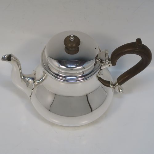 A very handsome Sterling Silver Bachelor size teapot, in a George I style with a plain round bellied body, having a hinged domed lid with wooden finial, a wooden insulated handle, a curved spout, and all sitting on a flat base. This elegant silver teapot was made by Charles Stuart Harris of London in 1923. The dimensions of this fine hand-made silver Bachelor teapot are height 14 cms (5.5 inches), length 21 cms (8.25 inches), and it weighs approx. 445g (14 troy ounces).