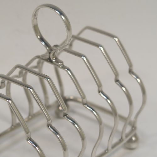 A very elegant Antique Sterling Silver seven-bar toastrack, having plain shaped cross-section wire-work bars, a matching loop handle, and all sitting on a rectangular base with four cast ball feet. This handsome antique silver toast-rack was made by Alexander Clark and Co. Ltd., of Birmingham in 1918. The dimensions of this fine hand-made antique silver toast-rack are length 13 cms (5 inches), height 12 cms (4.75 inches), width 8 cms (3.25 inches), and it weighs approx. 160g (5.2 troy ounces).