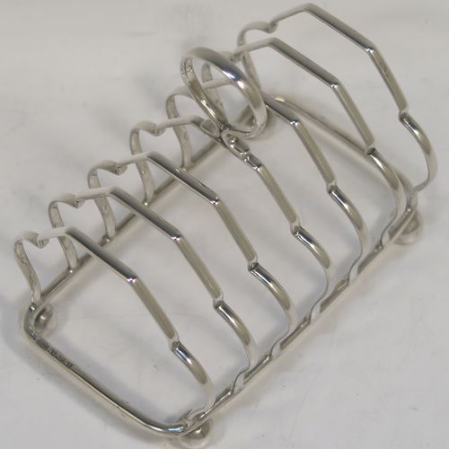 A very elegant Antique Sterling Silver seven-bar toastrack, having plain shaped cross-section wire-work bars, a matching loop handle, and all sitting on a rectangular base with four cast ball feet. This handsome antique silver toast-rack was made by Alexander Clark and Co. Ltd., of Birmingham in 1918. The dimensions of this fine hand-made antique silver toast-rack are length 13 cms (5 inches), height 12 cms (4.75 inches), width 8 cms (3.25 inches), and it weighs approx. 160g (5.2 troy ounces).