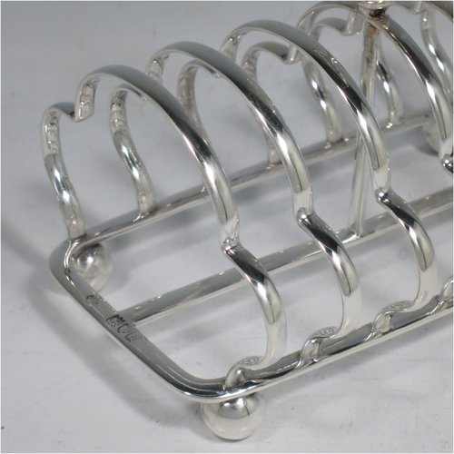 An Antique Victorian Sterling Silver large pair of seven-bar toast-racks, having shaped wire-work bars, matching loop handles, and sitting on rectangular bases with four ball feet. Made William Hutton of London in 1899/1900. The dimensions of this fine hand-made pair of silver toastracks are length 16 cms (6.25 inches), height 15 cms (6 inches), width 11 cms (4.25 inches), and they weigh approx. 612g (19.7 troy ounces).