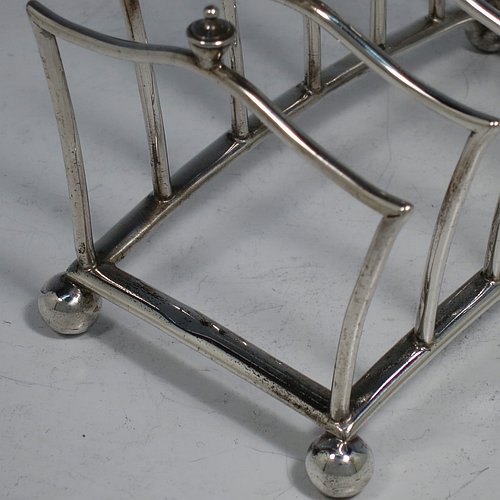 An Antique Victorian Sterling Silver Gothic style large and heavy seven-bar toast-rack, having unusual shaped square wire-work bars all with cast urn-shaped finials, a matching handle, sitting on a curved rectangular base, and four ball feet. Made by Martin & Hall of London in 1883. The dimensions of this fine hand-made antique silver toastrack are length 13.5 cms (5.25 inches), height 13 cms (5 inches), width 8 cms (3.25 inches), and it weighs approx. 222g (7.2 troy ounces).