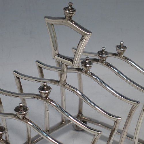 An Antique Victorian Sterling Silver Gothic style large and heavy seven-bar toast-rack, having unusual shaped square wire-work bars all with cast urn-shaped finials, a matching handle, sitting on a curved rectangular base, and four ball feet. Made by Martin & Hall of London in 1883. The dimensions of this fine hand-made antique silver toastrack are length 13.5 cms (5.25 inches), height 13 cms (5 inches), width 8 cms (3.25 inches), and it weighs approx. 222g (7.2 troy ounces).
