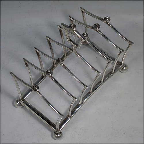 An Antique Victorian Sterling Silver Gothic style large and heavy seven-bar toast-rack, having unusual shaped square wire-work bars all with cast urn-shaped finials, a matching handle, sitting on a curved rectangular base, and four ball feet. Made by Martin & Hall of London in 1883. The dimensions of this fine hand-made antique silver toastrack are length 13.5 cms (5.25 inches), height 13 cms (5 inches), width 8 cms (3.25 inches), and it weighs approx. 222g (7.2 troy ounces).