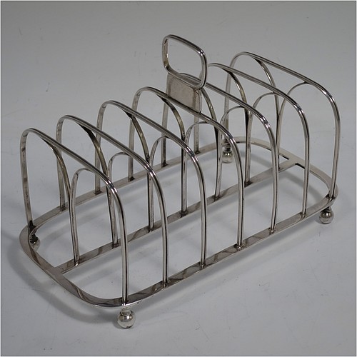 A very handsome Antique Georgian Sterling Silver seven-bar toast-rack, having rectangular shaped wire-work bars with hand-chased reeded decoration, a rectangular handle with vacant cartouche panel below, all attached to a flat rectangular base with strengthening struts, and sitting on four ball feet. Made by Joseph Biggs of London in 1816. The dimensions of this fine hand-made antique silver toast-rack are length 17 cms (6.75 inches), height 11 cms (4.25 inches), width 9 cms (3.5 inches), and it weighs approx. 162g (5.2 troy ounces).