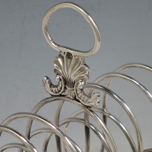 A very large and heavy Antique Georgian Sterling Silver seven-bar toast-rack, having shaped wire-work bars, a cast shell and loop handle, attached to a rectangular base with a strengthening strut, and sitting on four cast shell feet. Made by Robert and Samuel Hennell of London in 1809. The dimensions of this fine hand-made antique silver toast-rack are length 18.5 cms (7.25 inches), height 18.5 cms (7.25 inches), width 14 cms (5.5 inches), and it weighs approx. 550g (17.7 troy ounces).