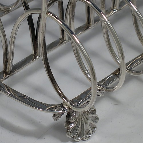 A very large and heavy Antique Georgian Sterling Silver seven-bar toast-rack, having shaped wire-work bars, a cast shell and loop handle, attached to a rectangular base with a strengthening strut, and sitting on four cast shell feet. Made by Robert and Samuel Hennell of London in 1809. The dimensions of this fine hand-made antique silver toast-rack are length 18.5 cms (7.25 inches), height 18.5 cms (7.25 inches), width 14 cms (5.5 inches), and it weighs approx. 550g (17.7 troy ounces).