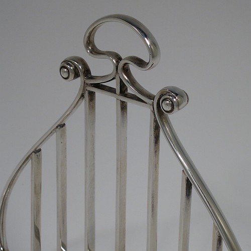 A Sterling Silver seven-bar toastrack or letter rack, having a very unusual Lyre style body with wire-work bars, a loop handle, and sitting on a base with a strengthening strut and four fluted and flanged feet. Made by Thomas Bradbury of Sheffield in 1937. The dimensions of this fine hand-made Lyre-shaped silver letter-rack or toast-rack are length 14 cms (5.5 inches), height 15 cms (6 inches), width 7 cms (2.75 inches), and it weighs approx. 202g (6.5 troy ounces).
