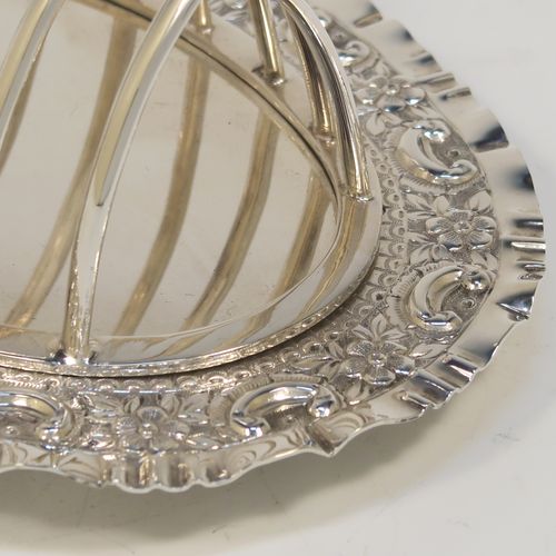 A very pretty Antique Victorian Silver Plated seven-bar toast-rack, having seven arch-shaped and graduated wire-work toast holders, attached to a crumb plate with a hand-chased scroll and floral decorated border, and all sitting on four ball feet. This beautiful antique toastrack was made by Joseph Rogers of Sheffield in ca. 1880. The dimensions of this fine hand-made antique silver-plated toast-rack are length 18 cms (7 inches), height 15 cms (6 inches), and width 13 cms (5 inches).