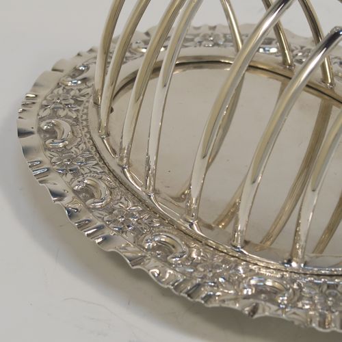 A very pretty Antique Victorian Silver Plated seven-bar toast-rack, having seven arch-shaped and graduated wire-work toast holders, attached to a crumb plate with a hand-chased scroll and floral decorated border, and all sitting on four ball feet. This beautiful antique toastrack was made by Joseph Rogers of Sheffield in ca. 1880. The dimensions of this fine hand-made antique silver-plated toast-rack are length 18 cms (7 inches), height 15 cms (6 inches), and width 13 cms (5 inches).